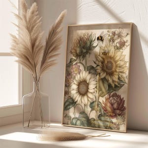 Puede incluir: Una impresi&oacute;n bot&aacute;nica enmarcada con girasoles, otras flores y una abeja. La obra de arte tiene una est&eacute;tica vintage con colores suaves y un marco dorado. Un jarr&oacute;n de cristal transparente con hierba de la pampa est&aacute; junto a la impresi&oacute;n enmarcada.