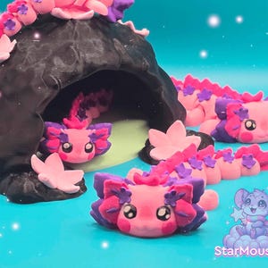 Puede incluir: Un grupo de figuras de ajolote rosa y morado con detalles de flores. Los ajolotes están colocados en un entorno de cueva con una figura de ajolote rosa y morado que emerge de la cueva.
