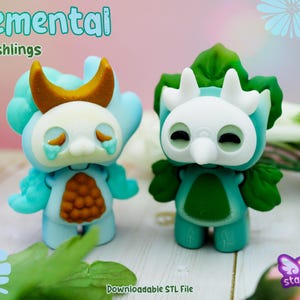Puede incluir: Dos figuras turquesas y blancas con el texto "Elemental Mooshlings". Una tiene un cuerno en forma de media luna y la otra tiene rasgos de hoja. Las figuras tienen una expresión triste. La imagen también incluye el texto "Downloadable STL File".