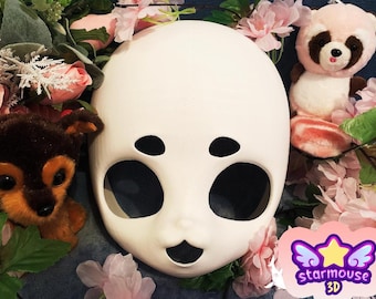 May include: A smooth white mask with large oval eye openings, small black eyebrow markings, and a small open mouth. The mask is surrounded by pink artificial flowers, a brown plush dog toy, and a pink plush raccoon toy. A logo reads starmouse 3D.