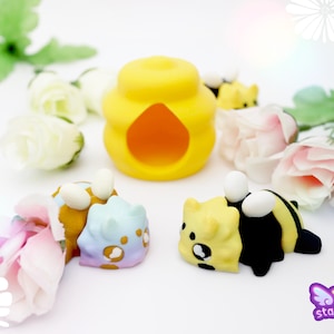 May include: A whimsical arrangement featuring a yellow beehive with an orange opening, surrounded by several cartoon bee figurines in yellow and black. Pastel-colored flowers and the "starmouse 3D" logo complete the scene.