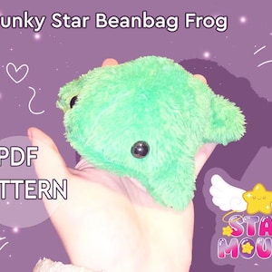 May include: A plush, green beanbag frog with black button eyes. The frog is held in a hand against a purple background. Text on the image reads "Chunky Star Beanbag Frog" and "PDF PATTERN". The Star Mouse logo is also visible.