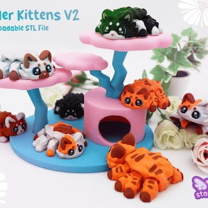Könnte beinhalten: Eine verspielte Darstellung von bunten Katzenfiguren. Die Kätzchen, in den Farbtönen Orange, Weiß, Schwarz und Grün, sind auf einer rosa-blauen, mehrstöckigen Struktur angeordnet. Der Text "ler Kittens V2" ist sichtbar.