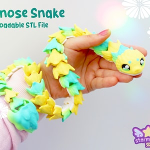 Peut inclure: Un jouet articulé Hognose Snake aux couleurs vives, jaune, bleu et vert. Le jouet est tenu dans une main, mettant en valeur sa conception flexible. Le texte "Hognose Snake" et "Downloadable STL File" est visible.