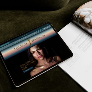 May include: A website homepage for Mystical & Bohemian, a business that offers services to help people gain clarity and discover a new path. The website features a woman with gold makeup and a dark background.