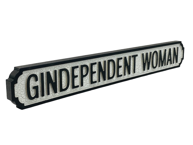 May include: A black and white sign with the text "Gindependent Woman" in black letters. The sign has a distressed, vintage look.