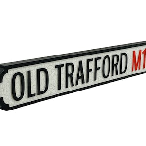 May include: Black and white street sign with the text "OLD TRAFFORD M16" in red letters.