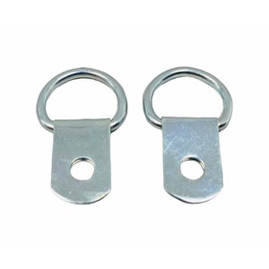 May include: Two silver metal D-ring picture hangers with a screw hole in the center of the flat base.
