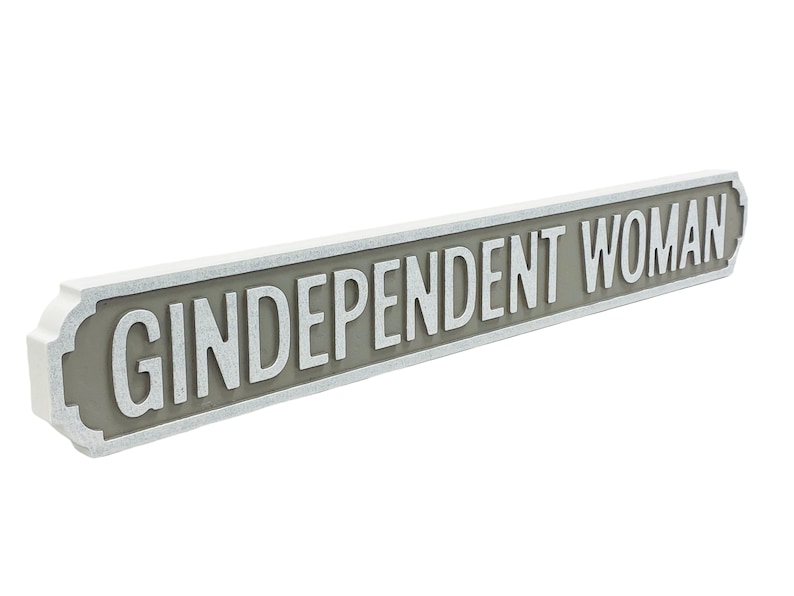 May include: A white and gray sign with the text "GINDEPENDENT WOMAN" in white lettering.