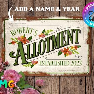 May include: A white sign with green and brown lettering that reads "Robert's Allotment Established 2023". The sign has a rustic, distressed look and is decorated with floral designs.