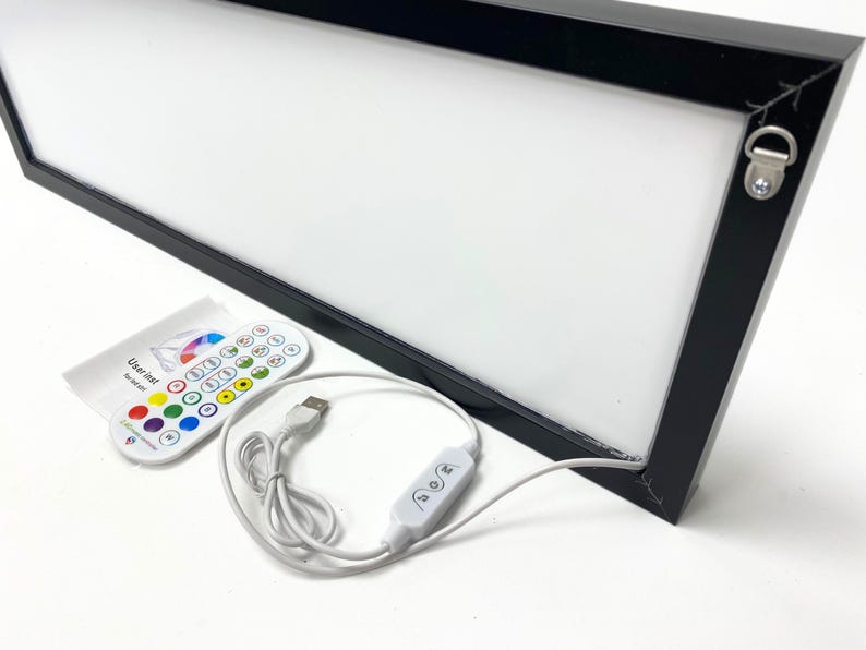 May include: A black framed light box with a white surface and a remote control. The light box is connected to a USB cable and has a switch to turn it on and off. The remote control has buttons for different colors and brightness levels. The light box is a great way to add a touch of color to any room.