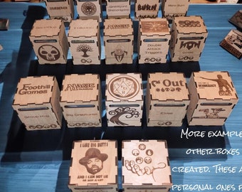 May include: A collection of wooden boxes with various designs and engravings. The boxes are labeled with names like "Foothill Games", "Magic", "Double Attack Triggers", "Hon", "Out", and "I Like Big Butts". The boxes are arranged on a blue surface. The text "More Examples of Other Boxes I've Created. These are my Personal Ones for my Pelican Case." is written below the boxes.