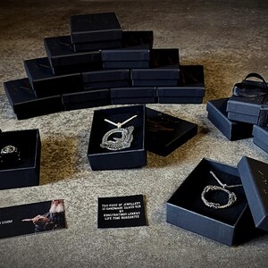 Może przedstawiać: Czarne pudełka z srebrną biżuterią w środku. Pudełka są ułożone na szarej powierzchni. Tekst "The Egg Studio Contemporary Jewellery" jest widoczny w lewym g&oacute;rnym rogu obrazu.