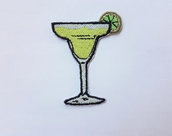 May include: An embroidered iron-on patch of a green margarita cocktail in a glass with a lime wedge on the rim.