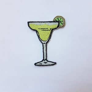 Op de afbeelding: Een geborduurde strijk-op patch van een groene margarita cocktail in een glas met een limoenwig op de rand.