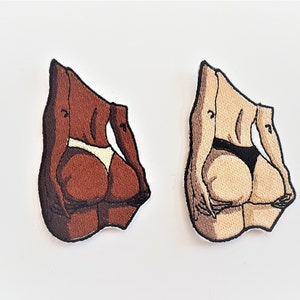 Puede incluir: Dos parches bordados que representan la parte posterior de una persona que lleva un traje de ba&ntilde;o. Un parche es marr&oacute;n y el otro es beige.