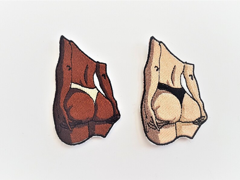 Puede incluir: Dos parches bordados que representan la parte posterior de una persona que lleva un traje de ba&ntilde;o. Un parche es marr&oacute;n y el otro es beige.