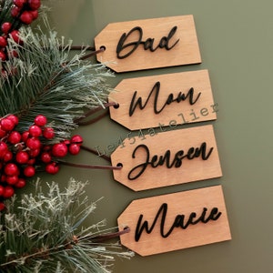May include: Four wooden gift tags with black cursive lettering. The tags read "Dad", "Mom", "Jensen", and "Macie".