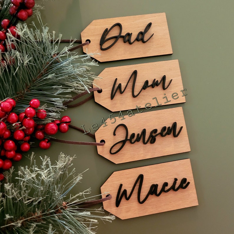 May include: Four wooden gift tags with black cursive lettering. The tags read "Dad", "Mom", "Jensen", and "Macie".