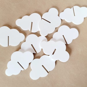Peut inclure: Neuf supports de cartes en forme de nuage blanc avec une fente pour ins&eacute;rer une carte. Les supports sont faits d'un mat&eacute;riau robuste et sont parfaits pour afficher des photos, des notes ou d'autres petits objets.