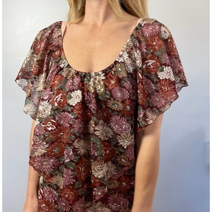 May include: A brown and green floral print dress with a ruffled neckline and short sleeves.