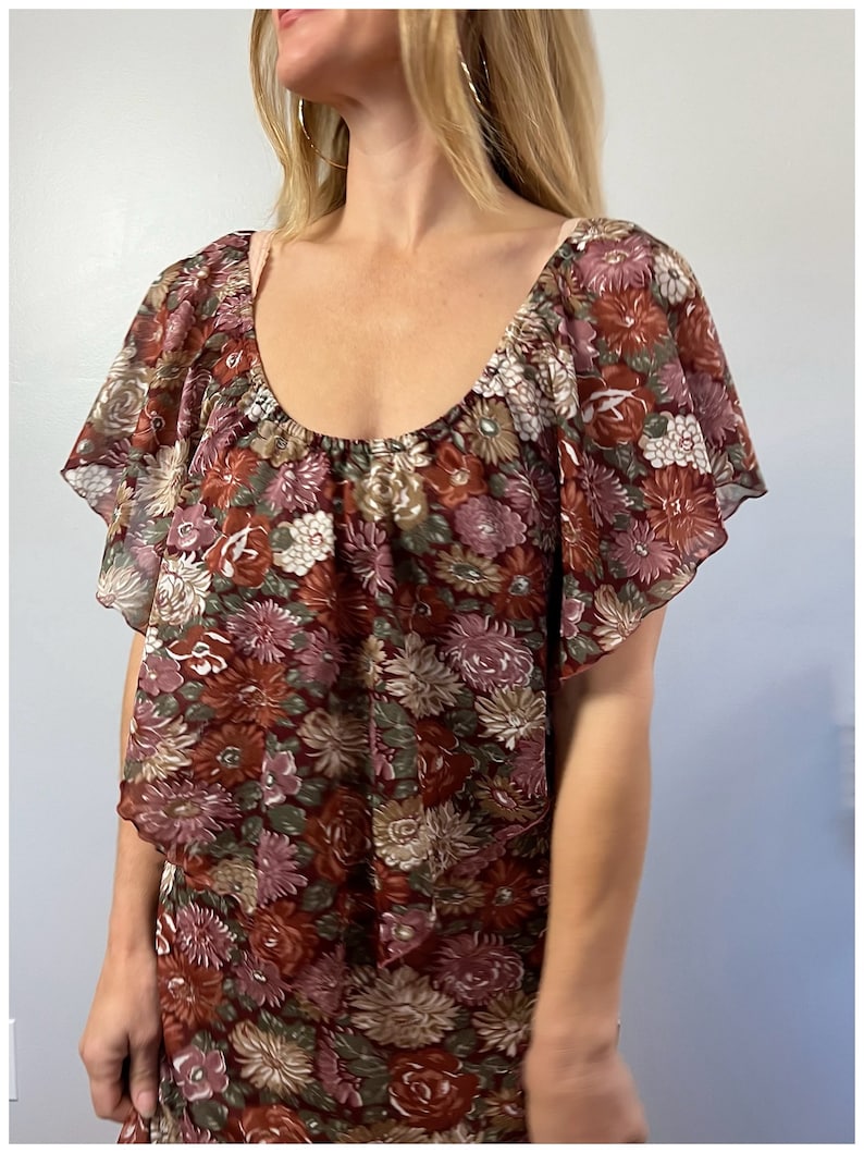 May include: A brown and green floral print dress with a ruffled neckline and short sleeves.