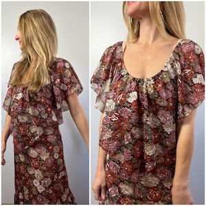 May include: A brown and pink floral print dress with a ruffled neckline and short sleeves. The dress has a tiered skirt and a relaxed fit.