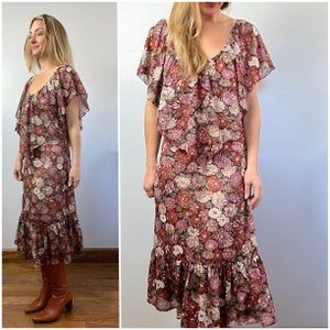 May include: A vintage floral print midi dress with a ruffled neckline and short sleeves. The dress has a tiered skirt with a ruffled hem and is made of a lightweight fabric.