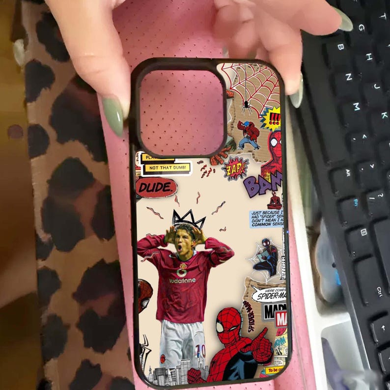 Puede incluir: Funda de tel&eacute;fono negra con un dise&ntilde;o de c&oacute;mic. Presenta a Spider-Man, bocadillos con palabras como "ZAP" y "BAM", y un futbolista. La funda tiene una est&eacute;tica de collage con varios elementos de texto.