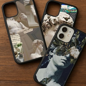 May include: Three black phone cases with unique designs. One case features a collage with a statue and the text "we exist in moments, nothing more." Another has a statue and text. The third case displays a statue with floral elements.