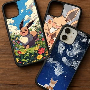May include: Three phone cases with black borders. One case features Eevee in a field of flowers under a blue sky. Another case shows Eevee smiling. The third case has a dark blue background with white illustrations.