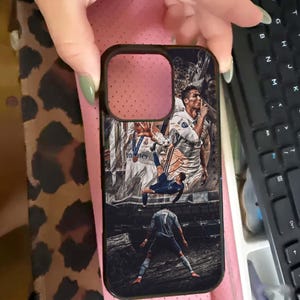 Puede incluir: Funda de tel&eacute;fono negra con un collage de un jugador de f&uacute;tbol en acci&oacute;n. El dise&ntilde;o incluye im&aacute;genes del jugador en diferentes poses, vistiendo varios uniformes del equipo. La funda tiene un borde negro y un recorte para la c&aacute;mara.