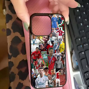 Puede incluir: Una funda de tel&eacute;fono negra con un collage de im&aacute;genes de un futbolista en varios uniformes y poses. La funda tiene un recorte para la c&aacute;mara y la sostiene una persona.