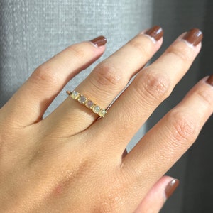 May include: A gold band ring with a row of seven white opal stones.