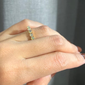 May include: A gold band ring with a row of round, white opals.