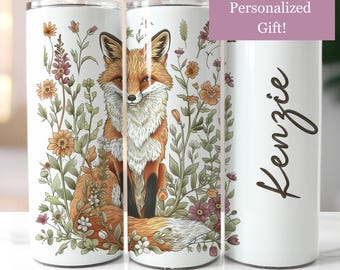 May include: A white stainless steel tumbler with a fox sitting in a field of flowers. The tumbler has a personalized name, "Kenzie", on the side.  Personalized Gift!
