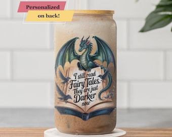 May include: A glass beverage cup with a bamboo lid and a straw. The cup features a dragon illustration with the text "I still read Fairy Tales, They are just Darker now." A banner reads "Personalized on back!"