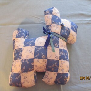 May include: A blue and pink patchwork dog toy. The dog is made of fabric squares with a floral pattern. The dog has a blue ribbon around its neck.