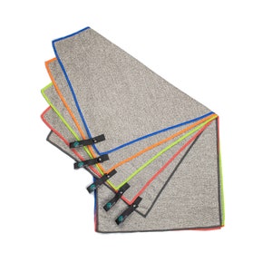 May include: Five gray microfiber towels with different colored trim, stacked on top of each other. The towels have a black strap with a green logo that says "Alter" on them.