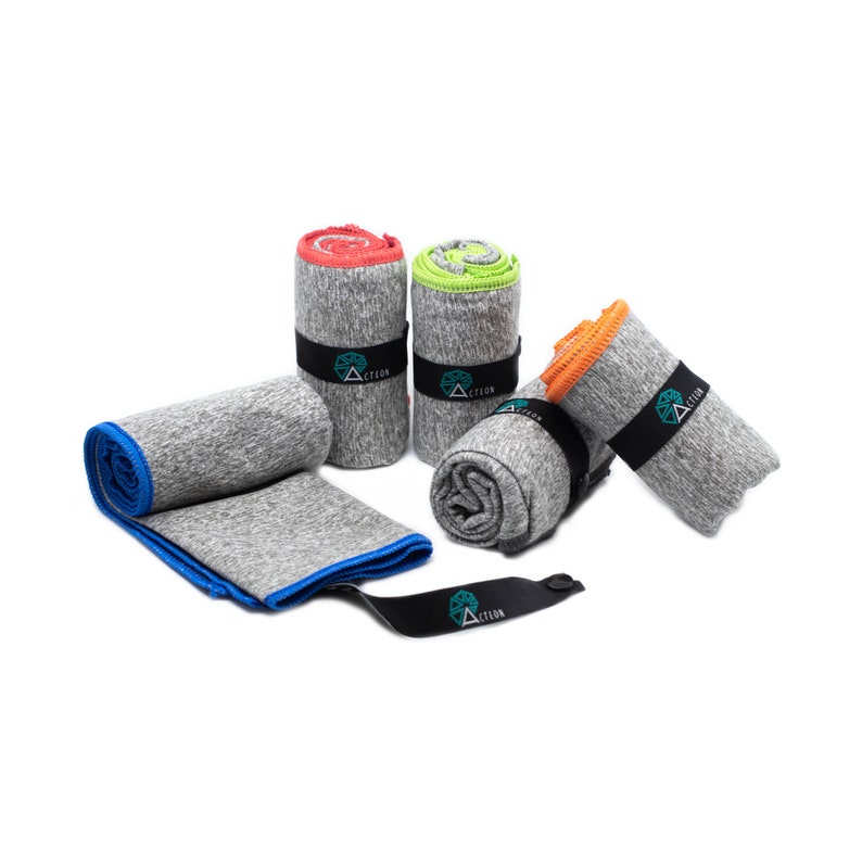 May include: Four gray microfiber towels with different colored trim, rolled up and tied with black straps. The straps have the word "ACTION" printed on them.