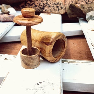 May include: A wooden salt cellar with a removable lid and a wooden pestle. The cellar is made of olive wood and has a natural wood finish.