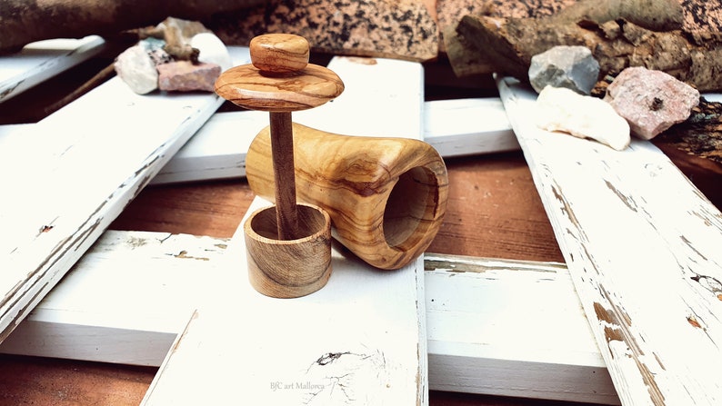 May include: A wooden salt cellar with a removable lid and a wooden pestle. The cellar is made of olive wood and has a natural wood finish.