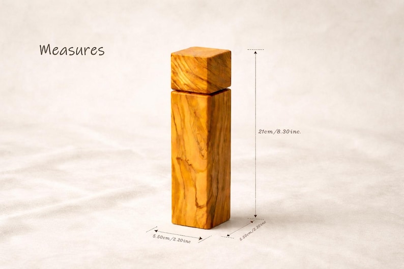 Op de afbeelding: Een houten zout- of pepermolen met een vierkante bovenkant en een rechthoekig lichaam. De molen is 21 cm hoog en 5,50 cm breed. Het hout heeft een natuurlijke, lichtbruine kleur met zichtbare nerf.
