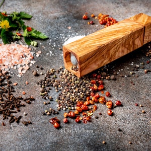 Pode incluir: Um moinho de pimenta de madeira de cor castanho claro com um padr&atilde;o de gr&atilde;o de madeira natural. O moinho &eacute; rodeado por v&aacute;rias especiarias, incluindo sal rosa do Himalaia, gr&atilde;os de pimenta preta, gr&atilde;os de pimenta branca, cravos e flocos de pimenta vermelha.