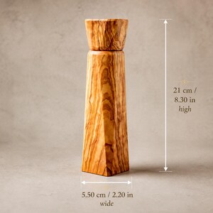 Pu&ograve; includere: Un macinapepe in legno, alto 21 cm e largo 5,50 cm, con finitura naturale a venature del legno. Il macinapepe ha una parte superiore cilindrica e un corpo geometrico angolare. Il colore del legno varia dal marrone chiaro al medio.