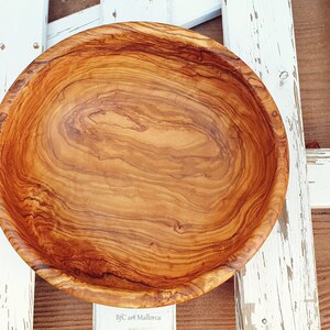 Large salad bowl or round fruit bowl made of olive wood. Salad bowl with drawings of highly veined wood. Medium brown colour. Top side view of the salad bowl. Top views