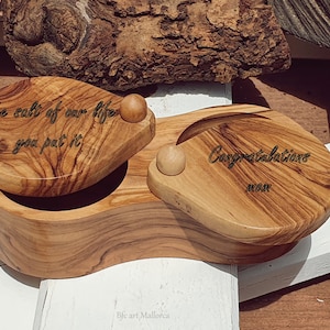 Könnte beinhalten: Eine Holzkiste mit zwei Deckeln, jeder mit einer anderen Inschrift. Der obere Deckel lautet "The salt of our life you put it" und der untere Deckel lautet "Congratulations mom".