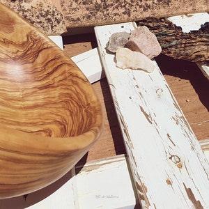 Large salad bowl or round fruit bowl made of olive wood. Salad bowl with highly grained wood drawings. Medium brown colour. Top side view of the salad bowl.