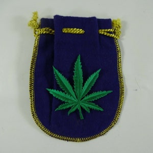May include: A small purple velvet pouch with a gold drawstring and a green marijuana leaf embroidered on the front.