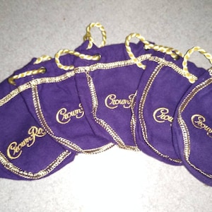 May include: Six purple velvet drawstring bags with gold trim and the words "Crown Royal" embroidered in gold.
